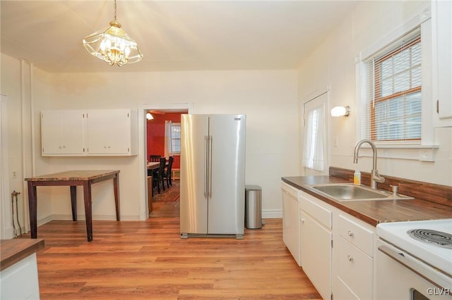 kitchen featuring high quality fridge, white cabinets, decorative light fixtures, sink, and a notable chandelier