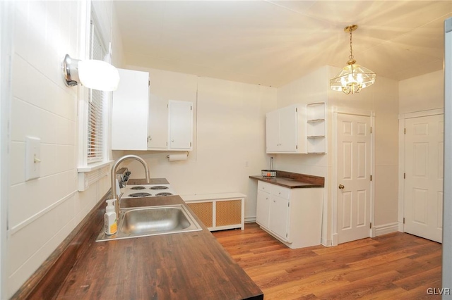 kitchen with pendant lighting, sink, hardwood / wood-style flooring, white cabinets, and radiator heating unit