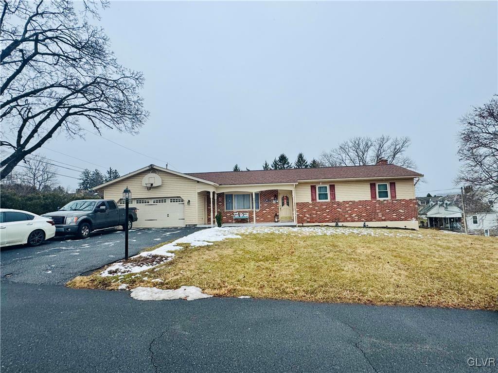 ranch-style home featuring a garage and a front lawn