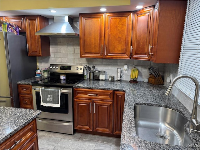 kitchen with appliances with stainless steel finishes, wall chimney range hood, decorative backsplash, sink, and light tile patterned flooring