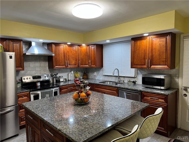 kitchen featuring stainless steel appliances, backsplash, wall chimney range hood, a kitchen island, and sink