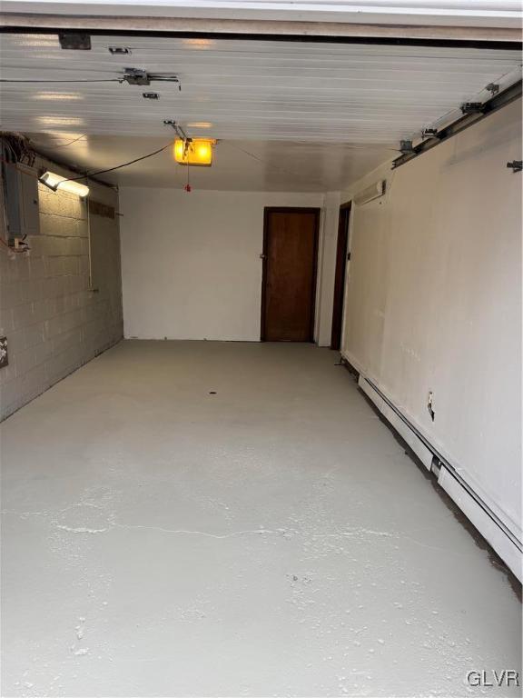 garage featuring a garage door opener, electric panel, and a baseboard radiator