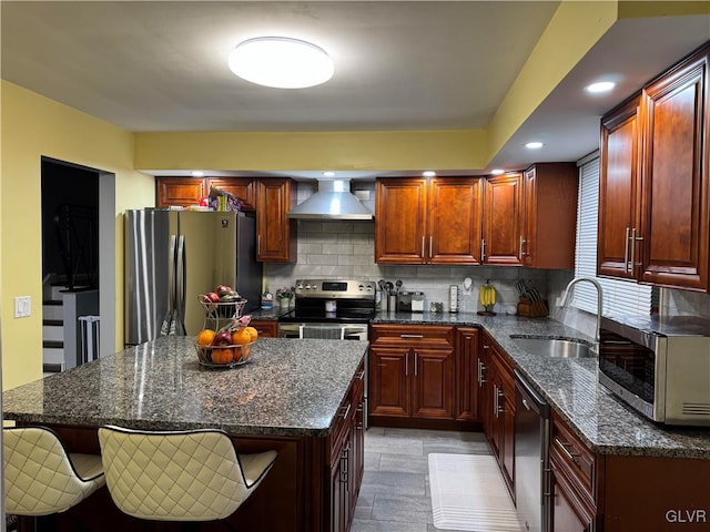 kitchen featuring wall chimney range hood, a center island, a kitchen bar, sink, and appliances with stainless steel finishes