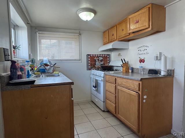 kitchen featuring white range with gas cooktop, light tile patterned floors, and sink