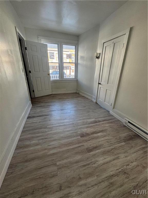 interior space featuring baseboard heating and dark hardwood / wood-style floors