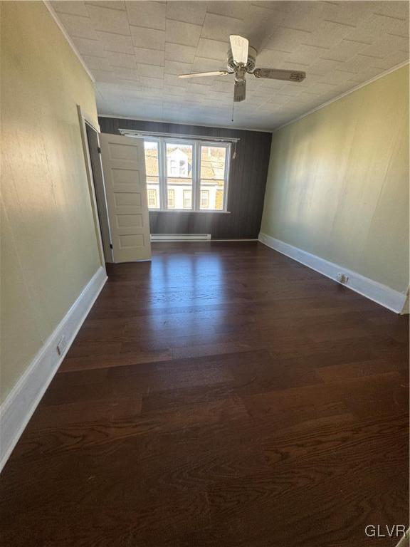 empty room featuring dark wood-type flooring, ornamental molding, and ceiling fan