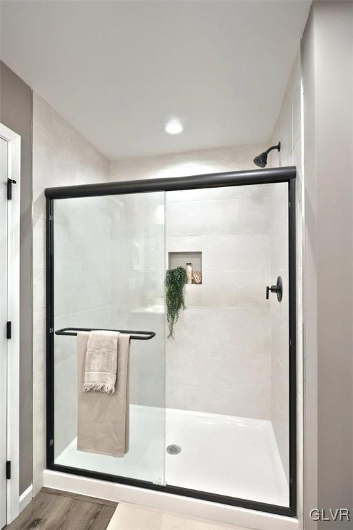 bathroom with wood-type flooring and a shower with door