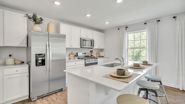 kitchen featuring stainless steel appliances, a kitchen island with sink, white cabinetry, and sink