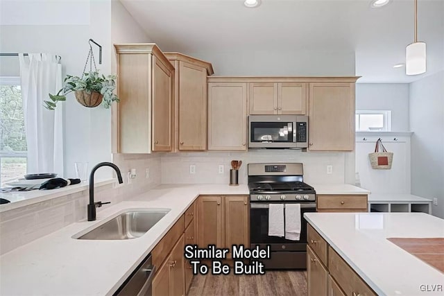 kitchen with appliances with stainless steel finishes, backsplash, light wood-type flooring, hanging light fixtures, and sink