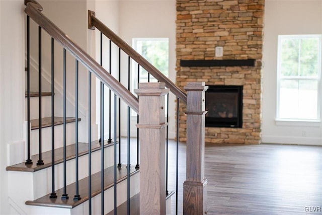 staircase featuring hardwood / wood-style flooring and a stone fireplace