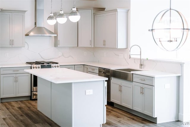 kitchen featuring appliances with stainless steel finishes, a kitchen island, decorative light fixtures, wall chimney range hood, and gray cabinets