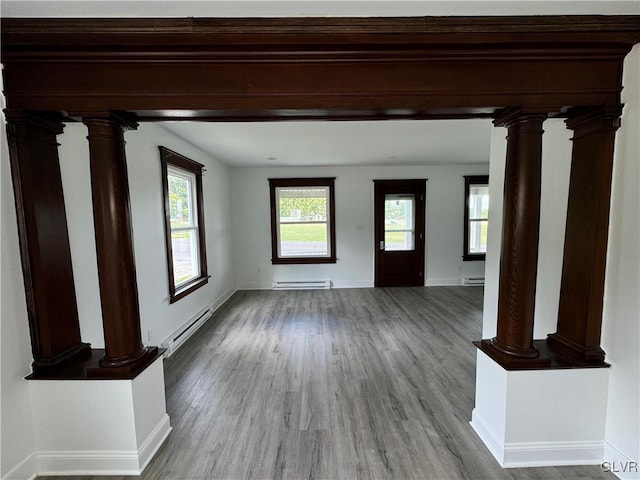 unfurnished living room featuring baseboard heating, light hardwood / wood-style floors, and decorative columns