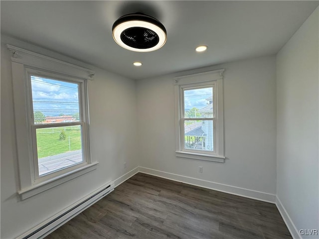 spare room with a baseboard heating unit and dark hardwood / wood-style floors