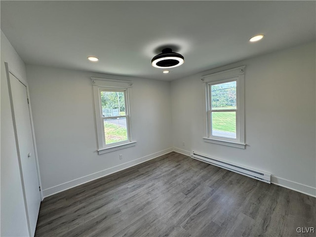 spare room with baseboard heating and dark wood-type flooring