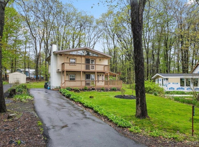 view of front facade featuring a front lawn, a deck, and a storage shed