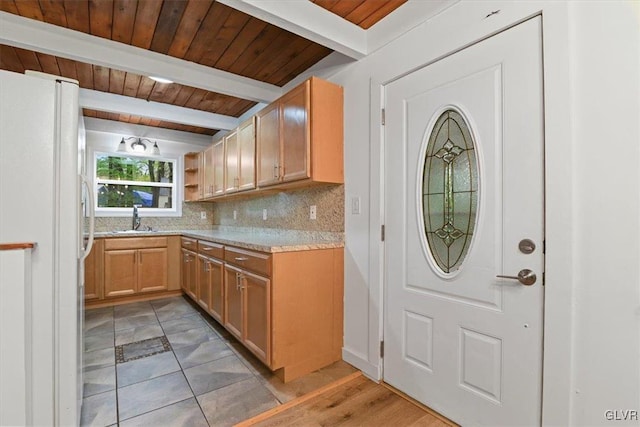 kitchen featuring white fridge, wooden ceiling, beamed ceiling, backsplash, and sink