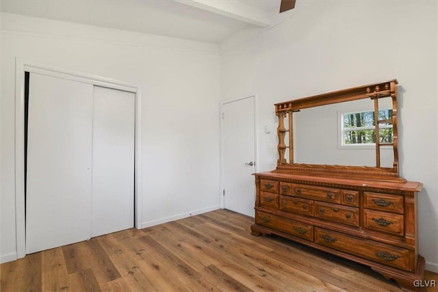 bedroom featuring a closet, beamed ceiling, hardwood / wood-style flooring, and ceiling fan