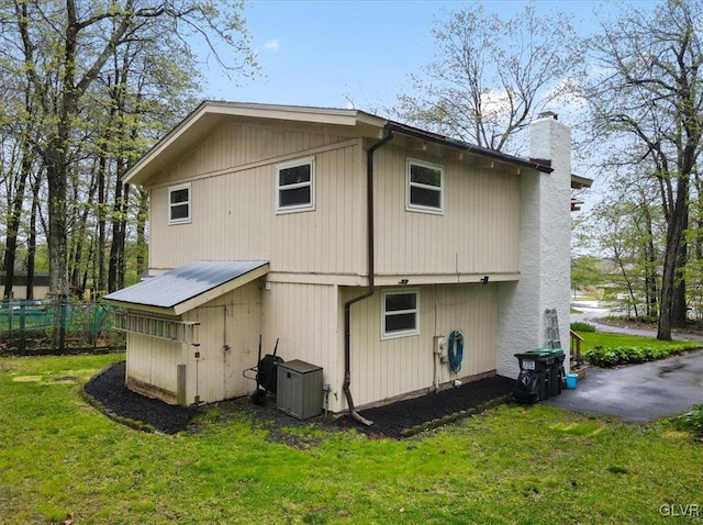 back of property featuring central AC unit and a yard