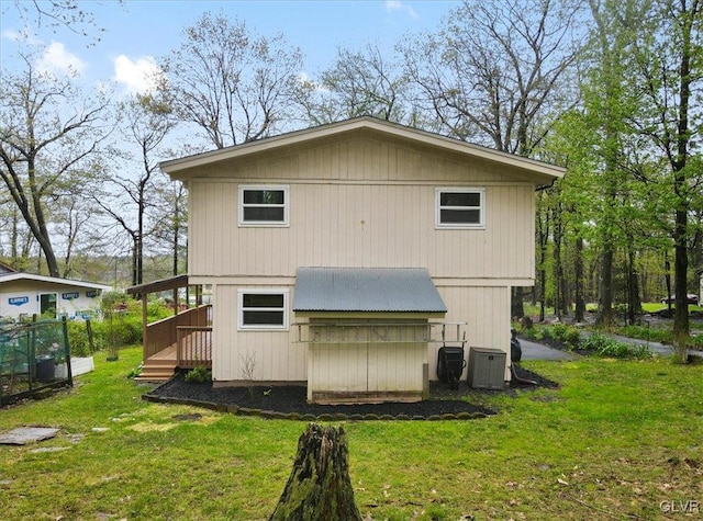 back of property with a wooden deck, a yard, and central air condition unit