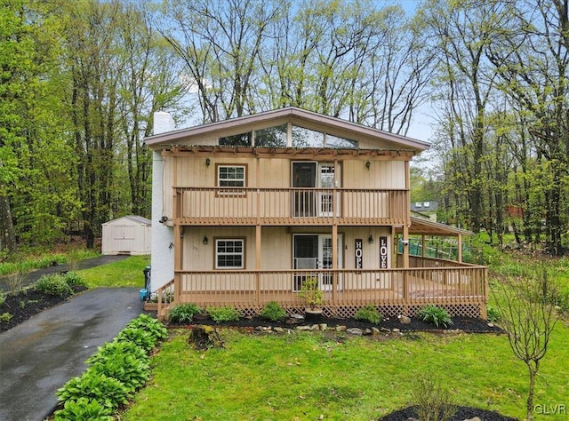 view of front facade featuring a front lawn, a shed, and a balcony