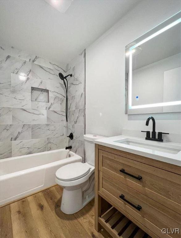 full bathroom with toilet, tiled shower / bath combo, wood-type flooring, and vanity