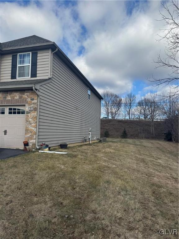 view of side of property featuring a garage and a lawn