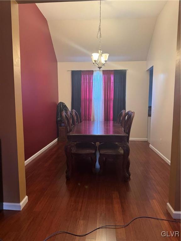 dining space with dark wood-type flooring, vaulted ceiling, and a notable chandelier