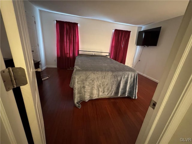 bedroom with baseboard heating and dark hardwood / wood-style flooring