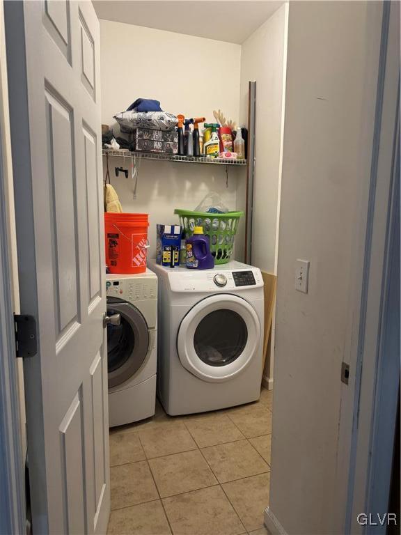 clothes washing area with washer and dryer and light tile patterned floors