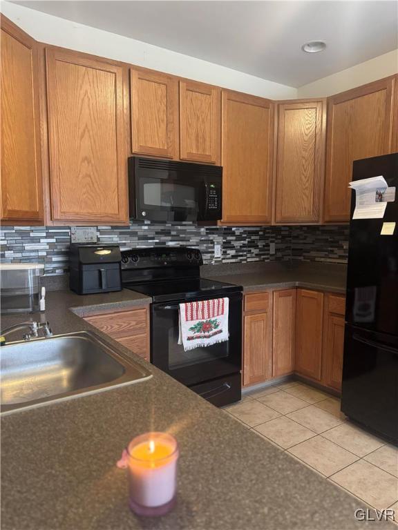 kitchen featuring light tile patterned flooring, sink, decorative backsplash, and black appliances