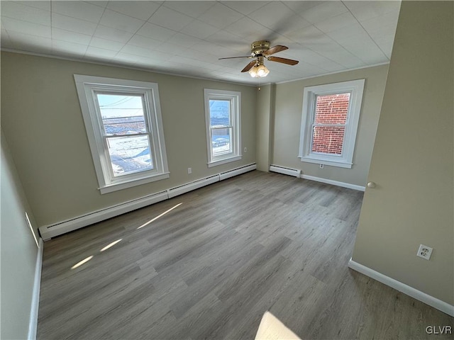 spare room featuring ceiling fan, a baseboard heating unit, crown molding, and light hardwood / wood-style flooring