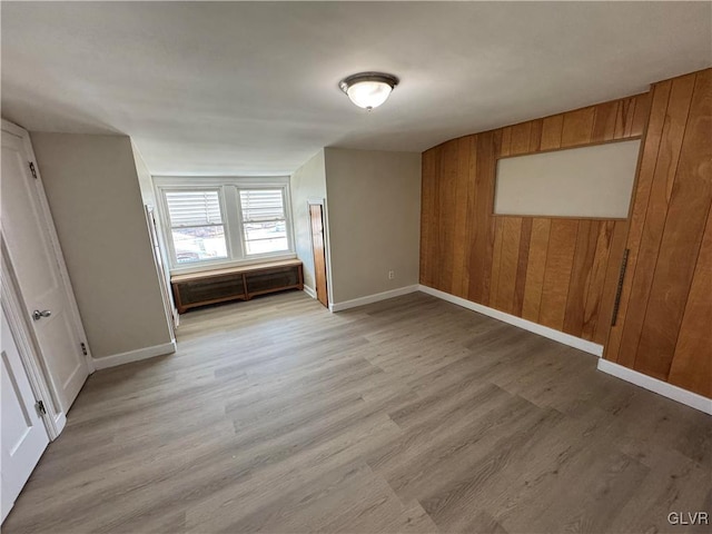 unfurnished room featuring light hardwood / wood-style floors and wood walls