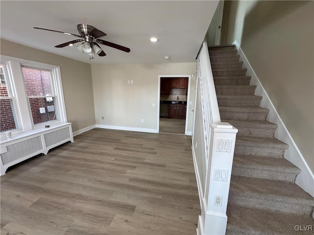 staircase featuring radiator, ceiling fan, wood-type flooring, and sink