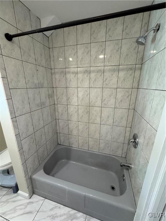 bathroom featuring toilet and tiled shower / bath