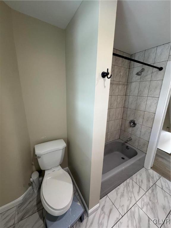 bathroom with toilet and tiled shower / bath combo