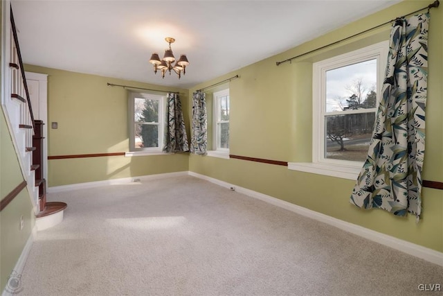 carpeted spare room featuring a healthy amount of sunlight and an inviting chandelier