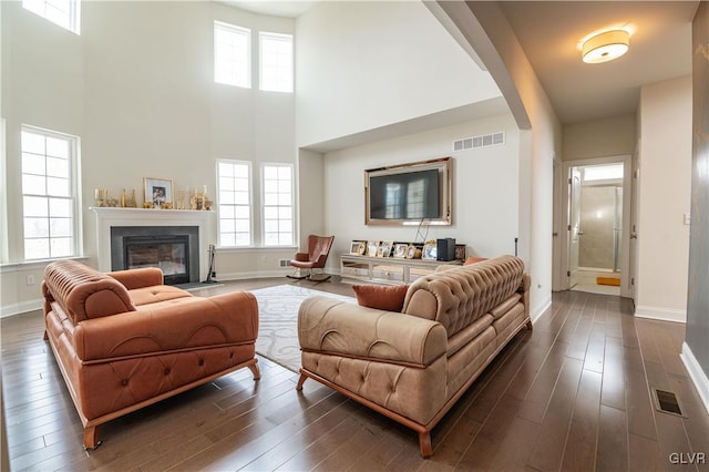 living room featuring dark wood-type flooring and a towering ceiling