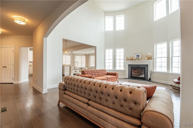 living room with dark hardwood / wood-style flooring and a towering ceiling