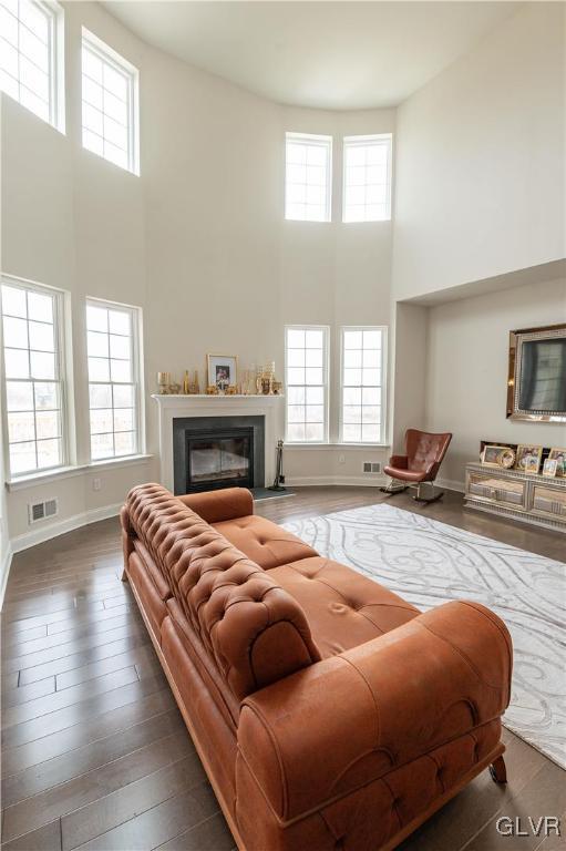 living room featuring a wealth of natural light, a towering ceiling, and dark hardwood / wood-style floors