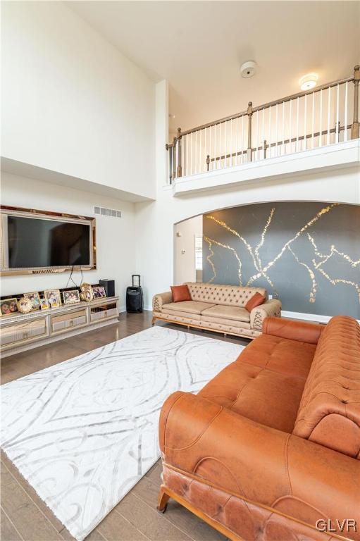 living room featuring a towering ceiling and hardwood / wood-style floors