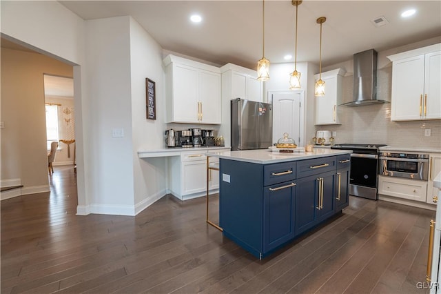 kitchen featuring white cabinets, appliances with stainless steel finishes, wall chimney exhaust hood, decorative light fixtures, and blue cabinets