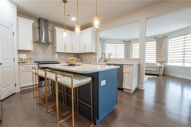 kitchen featuring appliances with stainless steel finishes, wall chimney exhaust hood, white cabinetry, and a center island