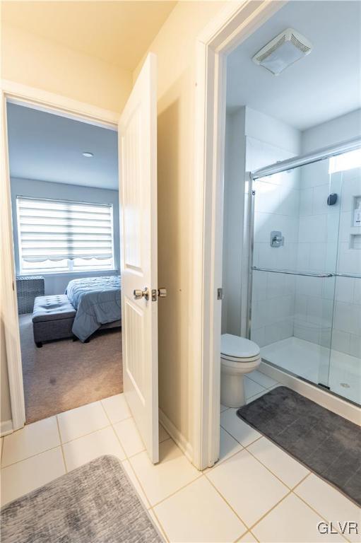 bathroom featuring a shower with shower door, tile patterned floors, and toilet