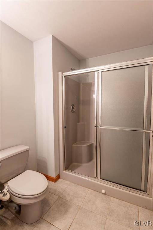 bathroom with toilet, tile patterned floors, and a shower with door