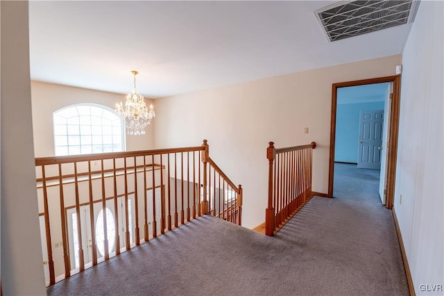 hallway with carpet and an inviting chandelier