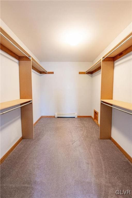 walk in closet with a baseboard radiator, light carpet, and built in desk