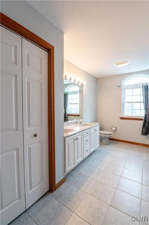 bathroom with toilet, a healthy amount of sunlight, tile patterned floors, and vanity