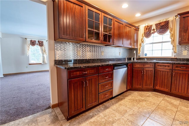 kitchen with light carpet, decorative backsplash, dark stone countertops, dishwasher, and sink