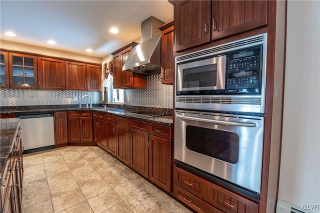 kitchen with sink, appliances with stainless steel finishes, wall chimney exhaust hood, and dark stone countertops