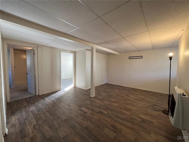 basement with heating unit, a paneled ceiling, and dark hardwood / wood-style flooring